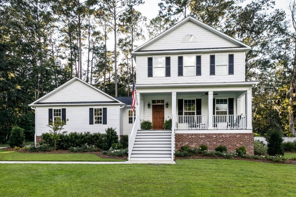 Two-story white siding home with attached single-story addition in a wooded Northern Virginia-style suburban setting